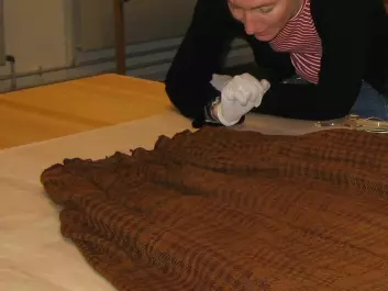 Archaeologist Ulla Mannering studying the skirt in the laboratory. (Photo: Colourbox)