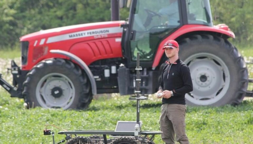 Karl Damkjær Hansen pictured next to a field robot. The researchers are hoping that within a couple of years the robot will replace the tractor in the background. (Photo: ASETA project)
