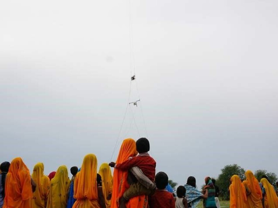 Local spectators watch on as a helicopter equipped with a new Danish airborne surveying technique goes on the lookout for fresh drinking water in India. (Photo: Esben Auken)