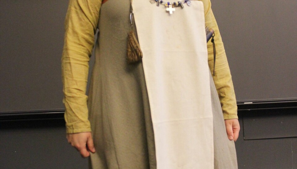 A complete female outfit with linen undergarments or smock, a strap dress with shell-shaped brooches, and a headscarf.
