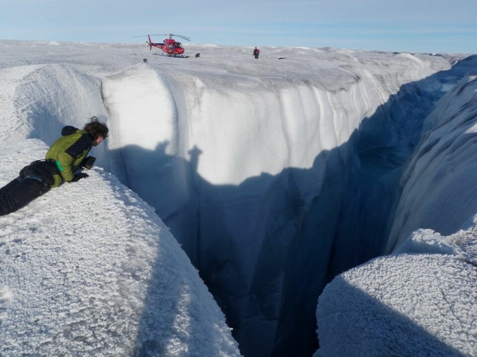 A monster moulin on the Russell Glacier, Greenland. You can see a helicopter for scale. These large gaping holes allow rain and melt water to drain quickly into the ice sheet. (Photo: Alun Hubbard)
