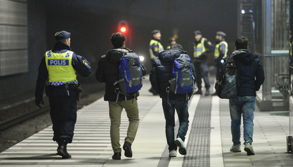 A police officer escorts migrants from a train at Hyllie station outside Malmo. (Photo: TT News Agency/Reuters)