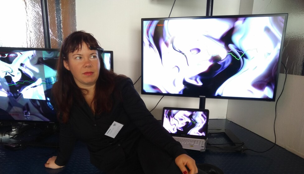 The scientist behind the project and author of this article, Marija Griniuk is trying on the EEG device herself. Her state of mind is visualized on the screen behind her.